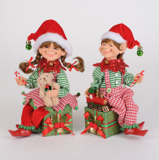 Two Christmas-themed dolls in festive outfits with presents and a teddy bear on a white background.